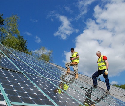 Workers inspecting Solar PV Panels on a roof