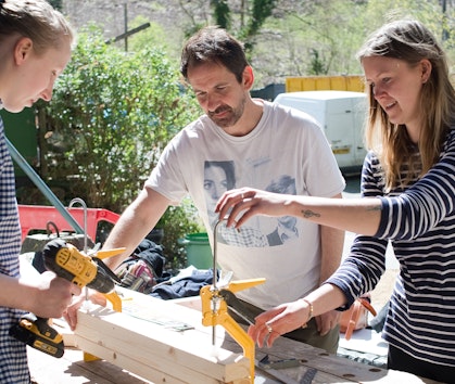 Three people working with wood on a building course